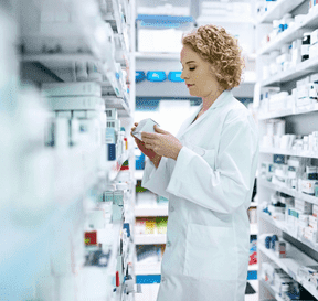 Lekárnička sa díva na krabičku liekov v regáloch s liekmi